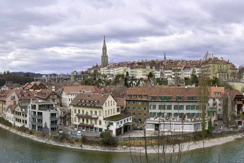 Berner Altstadt über der Aare mit Münsterturm unter bewölktem Himmel