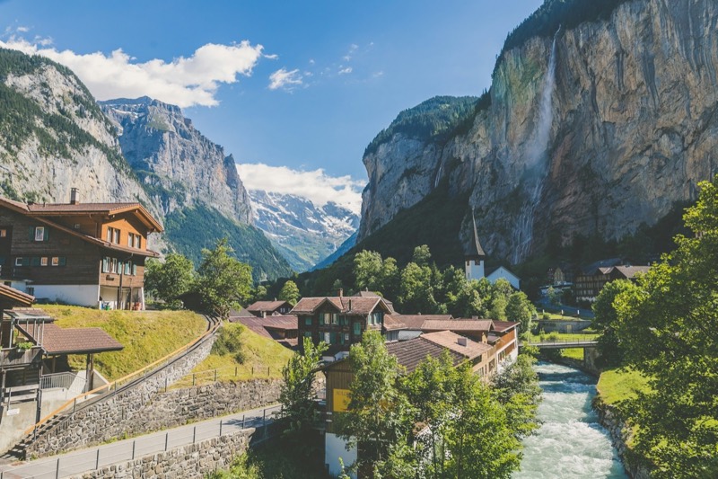 Lauterbrunnen mit Chalets, Staubbachfall an der Felswand und Bergen im Hintergrund