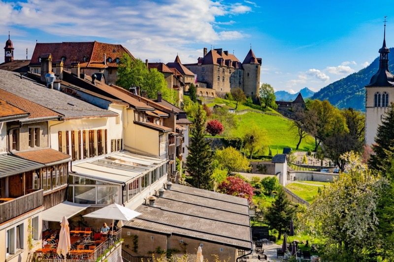 Städtchen Gruyères mit Schloss und Kirche, dahinter die Voralpen